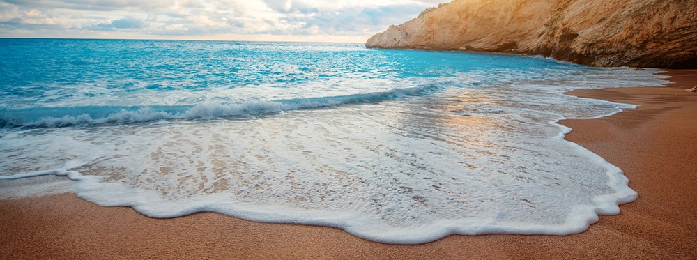 Waves rolling onto the beach, cliffs in the background