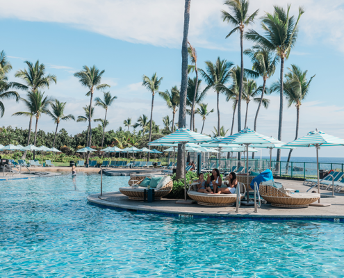 A family sitting around the pool at the OUTRIGGER Kona Resort & Spa