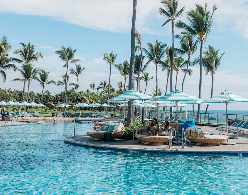 A family sitting around the pool at the OUTRIGGER Kona Resort & Spa